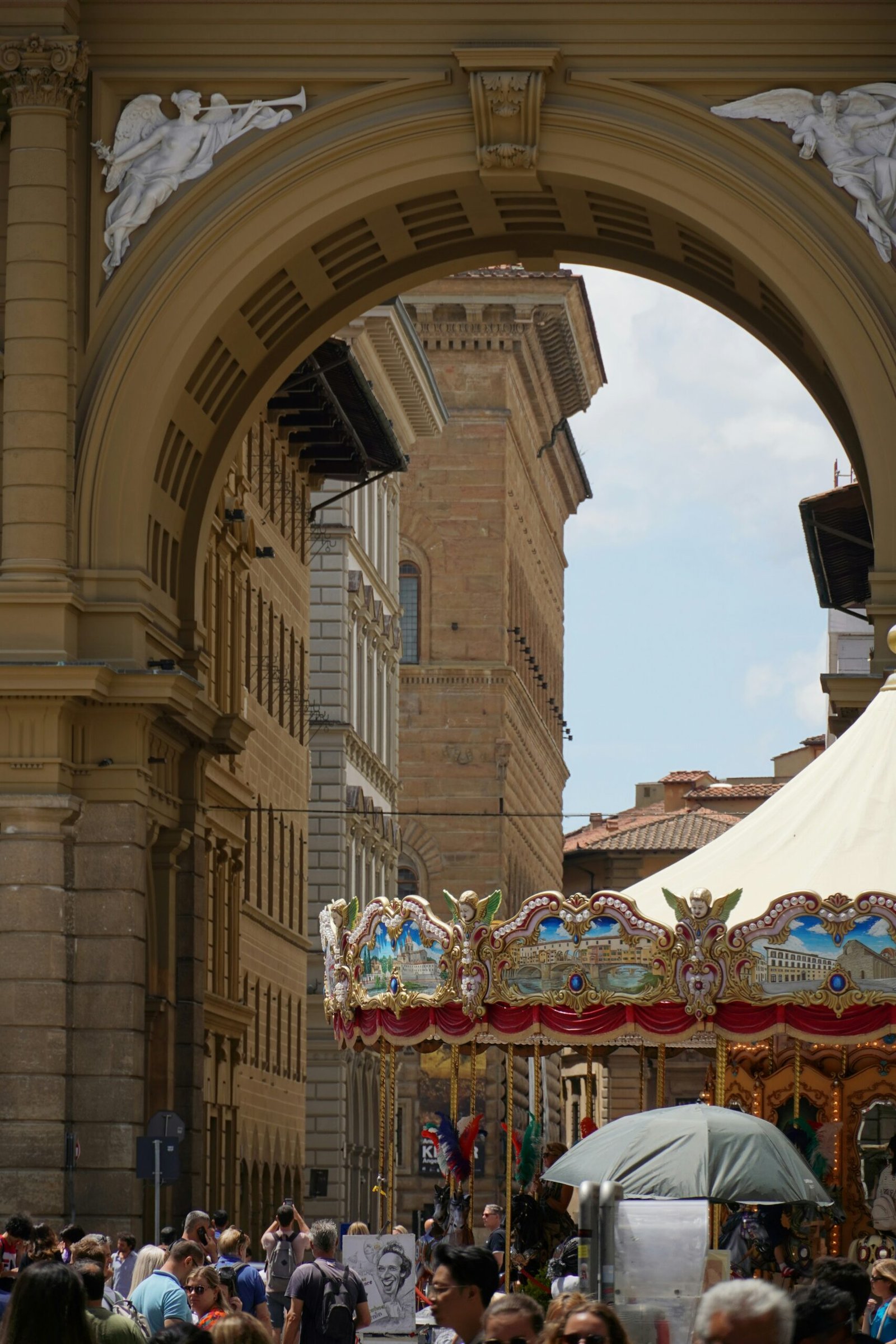 A crowd of people walking down a street under an archway