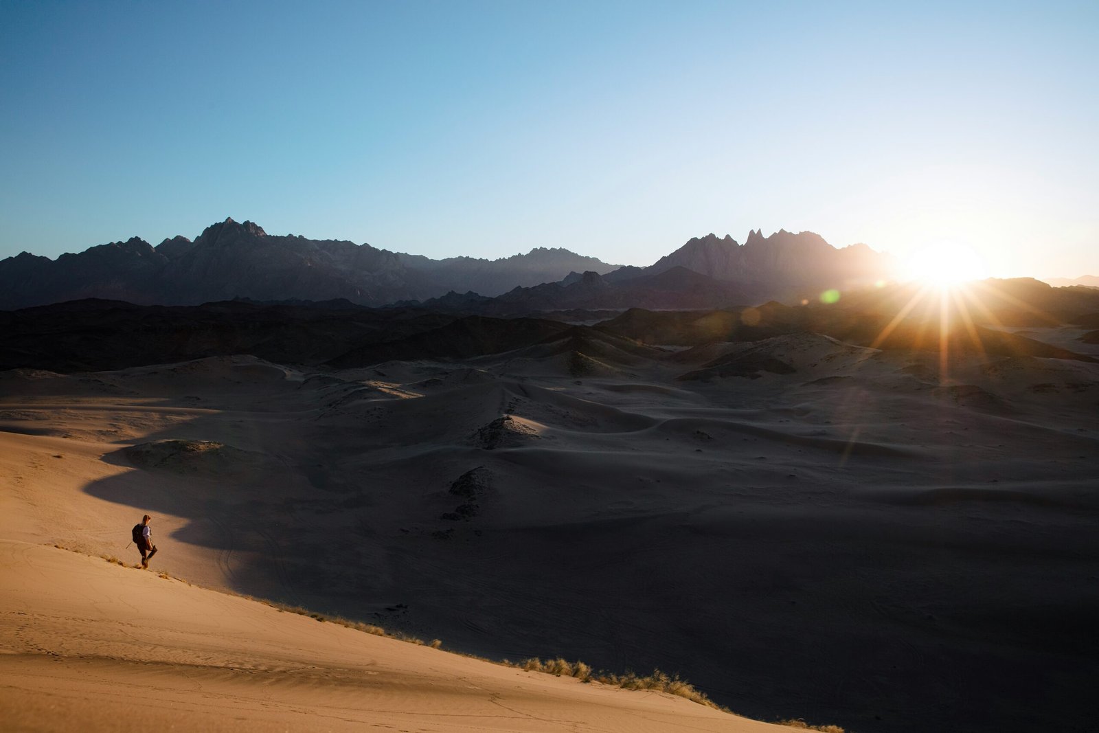 a person is walking in the desert at sunset