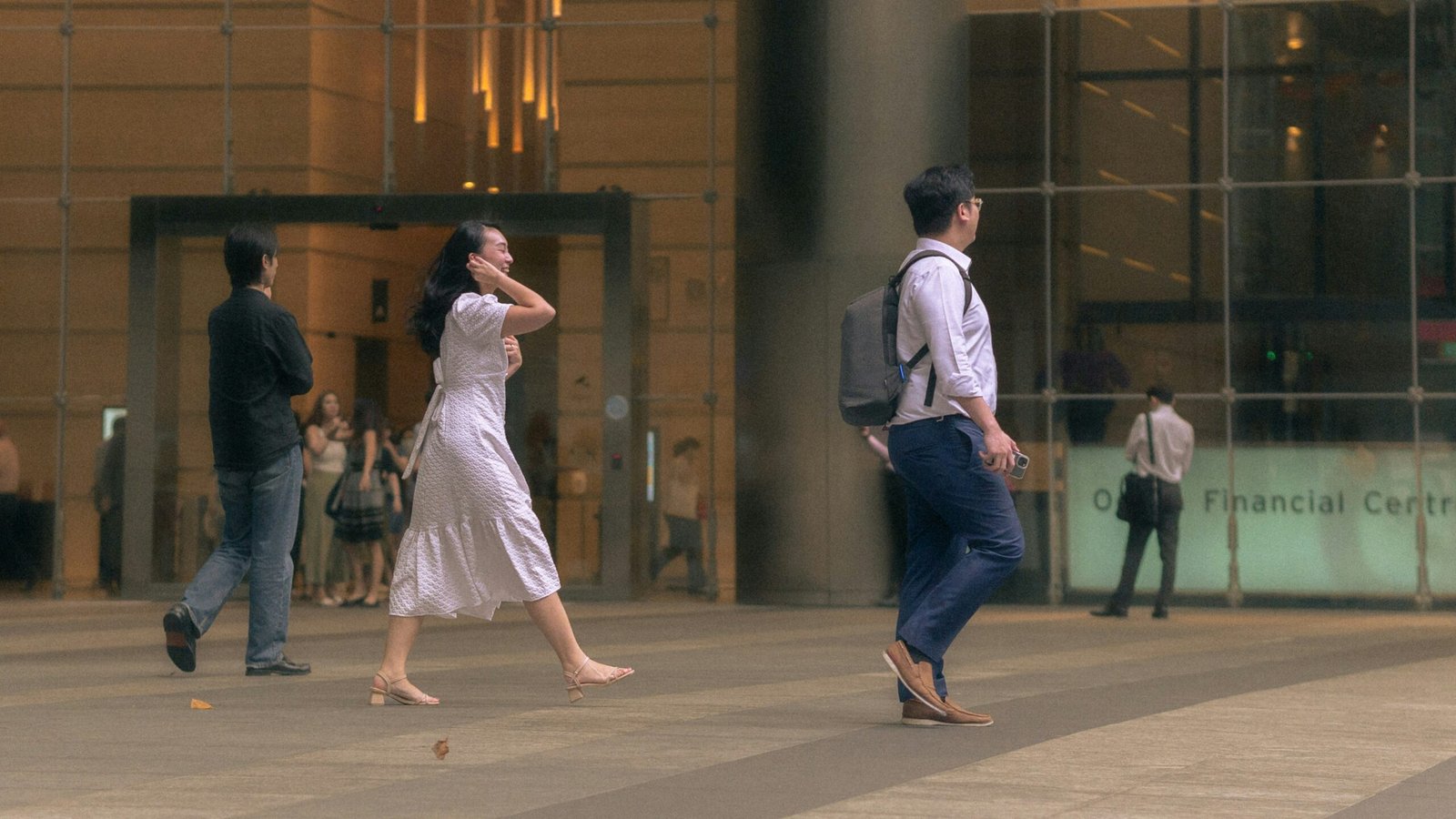 A group of people walking down a street next to a tall building